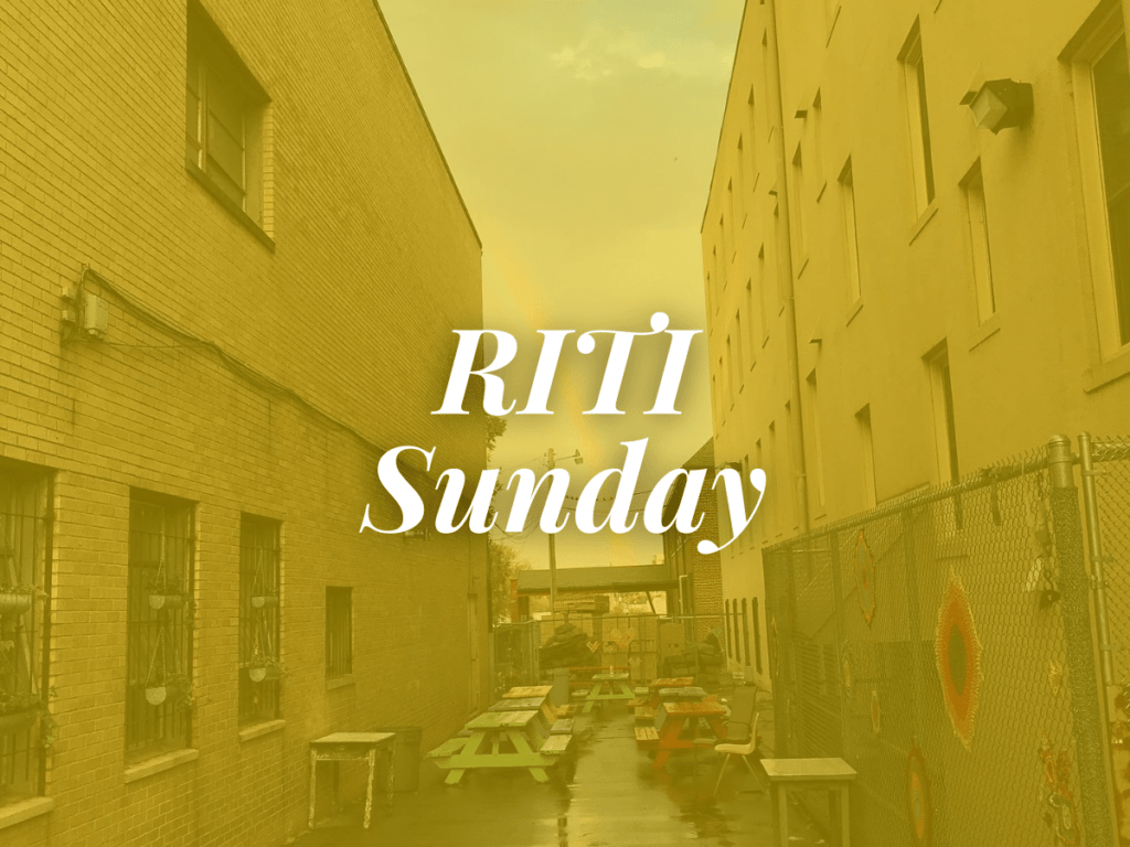 room in the inn blog title RITI Sunday overlaying image of alleyway filled with colorful picnic tables and rainbow overhead