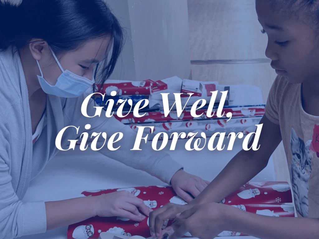 room in the inn blog title Give Well, Give Forward overlays image of volunteer and child wrapping holiday gift