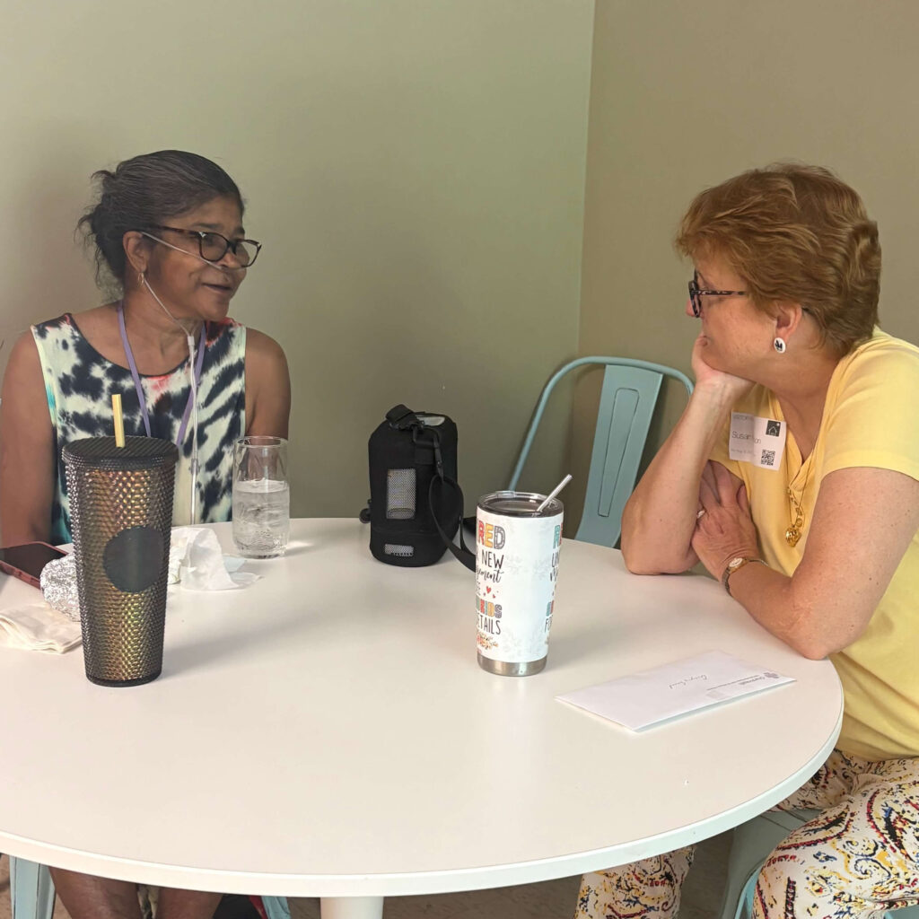 Dr. Susan Nelson sits at a table with RITI Guest, Gina, during a weekly visit to Room in the Inn.